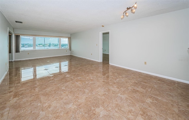 tiled spare room featuring a textured ceiling