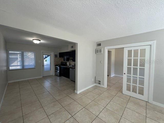 unfurnished living room with a textured ceiling and light tile patterned floors