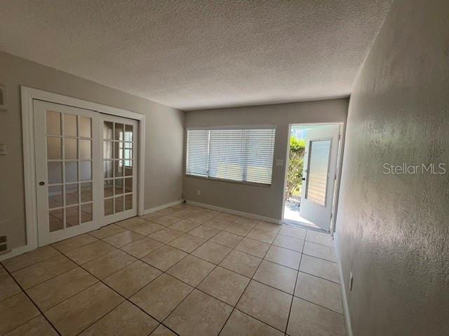 tiled empty room with a textured ceiling