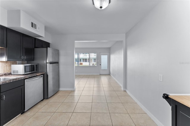 kitchen with stainless steel appliances, light tile patterned floors, and tasteful backsplash