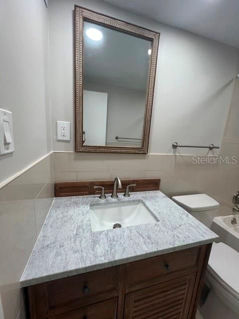 bathroom with tile walls, backsplash, vanity, and toilet