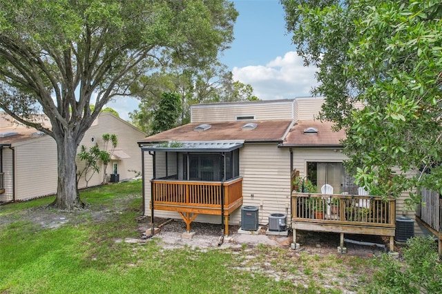 rear view of property featuring a sunroom, a yard, and central air condition unit