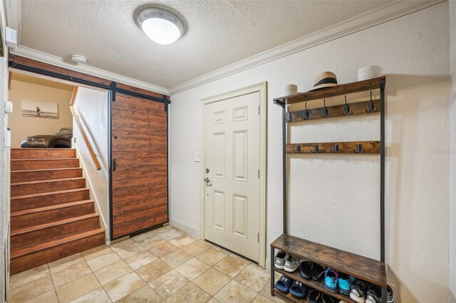 entrance foyer with light tile patterned floors, crown molding, a textured ceiling, and stairs