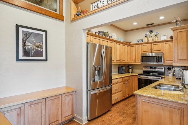 kitchen featuring light stone counters, a sink, visible vents, appliances with stainless steel finishes, and light wood finished floors