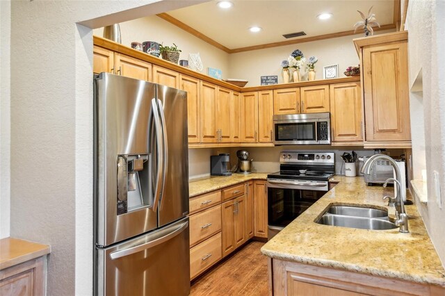 kitchen featuring visible vents, light stone counters, ornamental molding, stainless steel appliances, and a sink