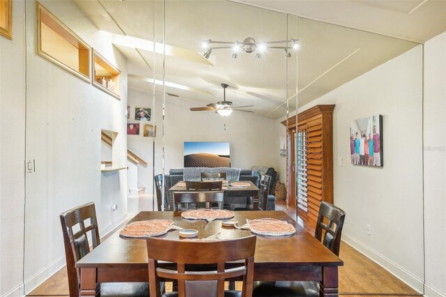 dining space with baseboards, ceiling fan, wood finished floors, stairs, and vaulted ceiling