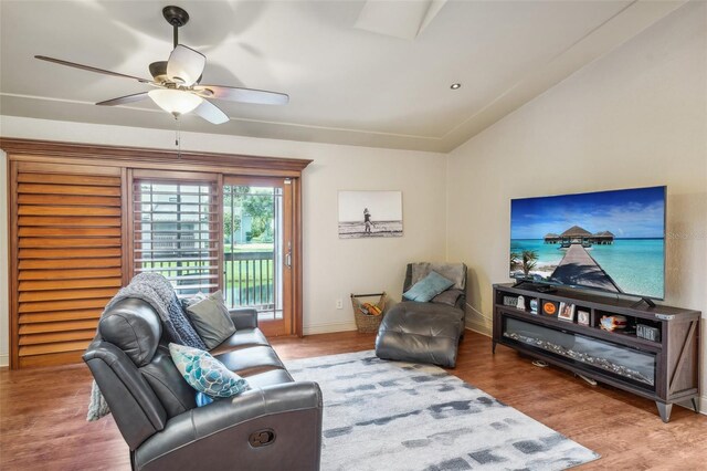 living room featuring a ceiling fan, baseboards, vaulted ceiling, and wood finished floors