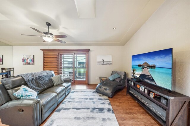 living area featuring lofted ceiling, baseboards, a ceiling fan, and wood finished floors