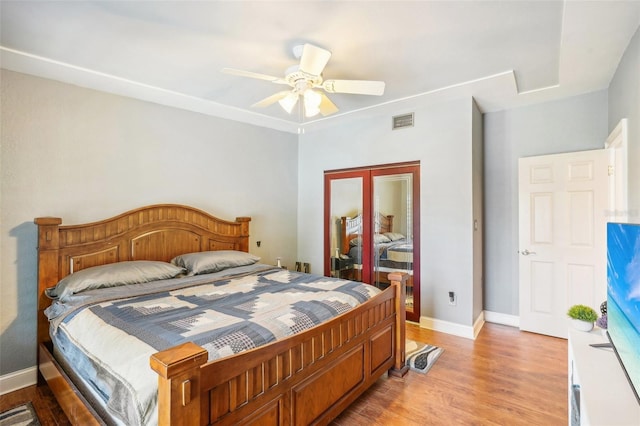 bedroom with a ceiling fan, light wood-type flooring, visible vents, and baseboards