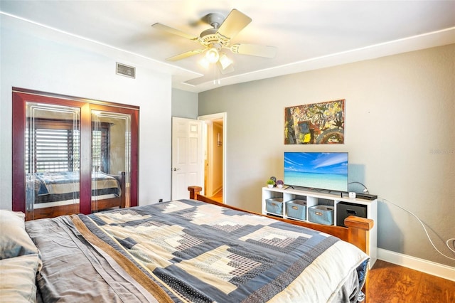 bedroom featuring ceiling fan, wood finished floors, visible vents, and baseboards