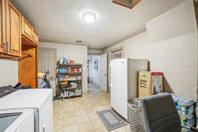 laundry room with cabinet space, light tile patterned floors, a textured wall, ornamental molding, and washing machine and clothes dryer