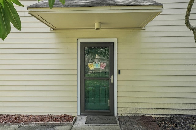 doorway to property featuring roof with shingles