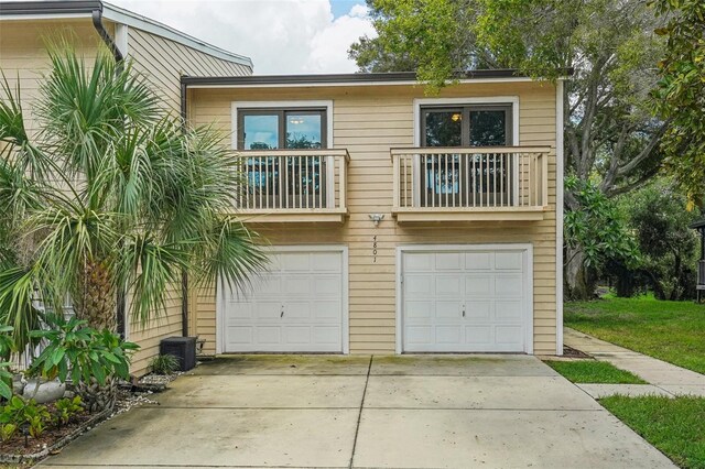 view of front facade featuring driveway, a balcony, central air condition unit, and a garage