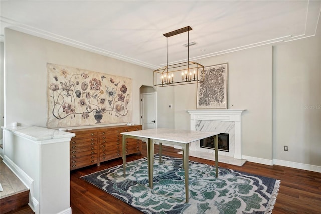 office area featuring an inviting chandelier, a premium fireplace, dark wood-type flooring, and ornamental molding