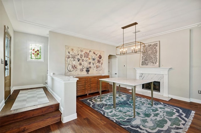 dining room featuring crown molding, dark hardwood / wood-style flooring, a fireplace, and a chandelier