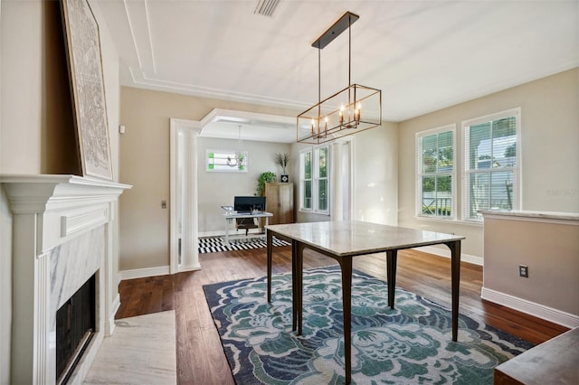 dining room featuring a high end fireplace, dark hardwood / wood-style flooring, and a notable chandelier