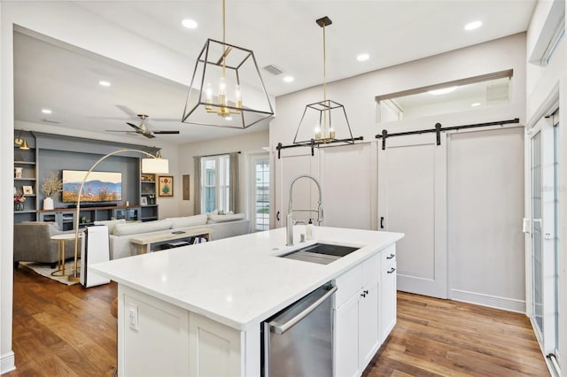 kitchen with a barn door, sink, a center island with sink, and hardwood / wood-style flooring