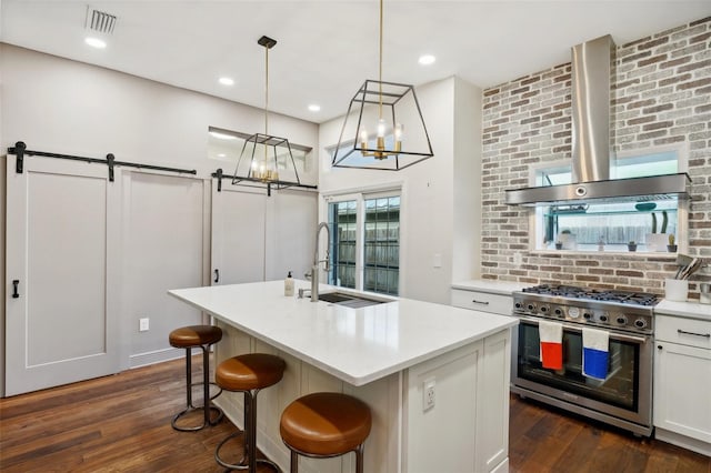 kitchen featuring sink, dark wood-type flooring, a barn door, an island with sink, and double oven range