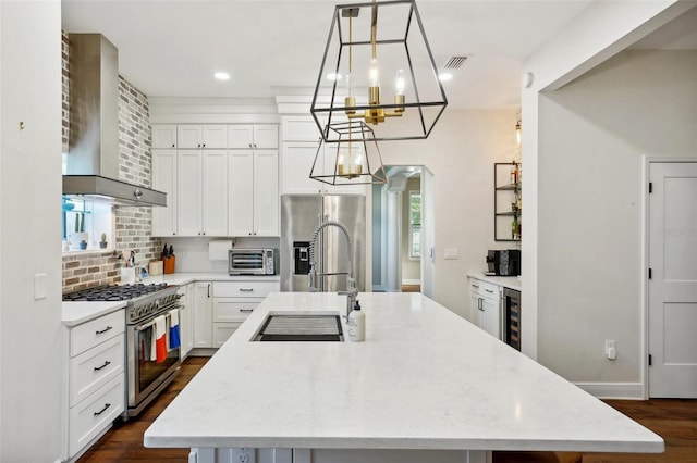 kitchen featuring light stone countertops, an island with sink, pendant lighting, and appliances with stainless steel finishes