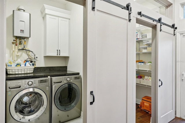 clothes washing area featuring cabinets, tankless water heater, a barn door, washing machine and dryer, and dark hardwood / wood-style floors