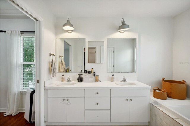 bathroom with tiled tub, vanity, and hardwood / wood-style flooring