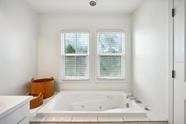 bathroom with tiled tub and vanity