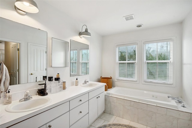 bathroom featuring tiled tub, tile patterned flooring, and vanity