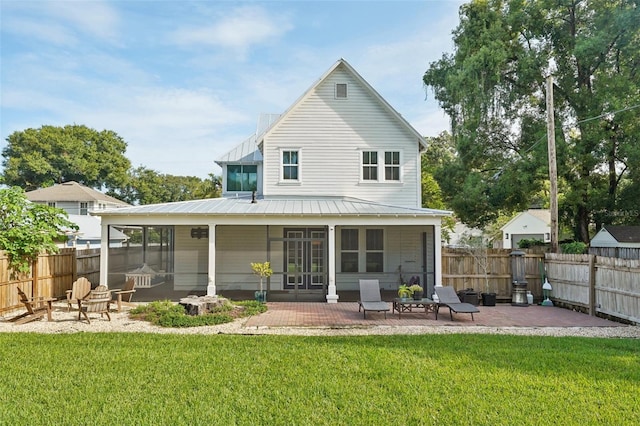 back of house featuring a patio, a fire pit, a lawn, and a sunroom