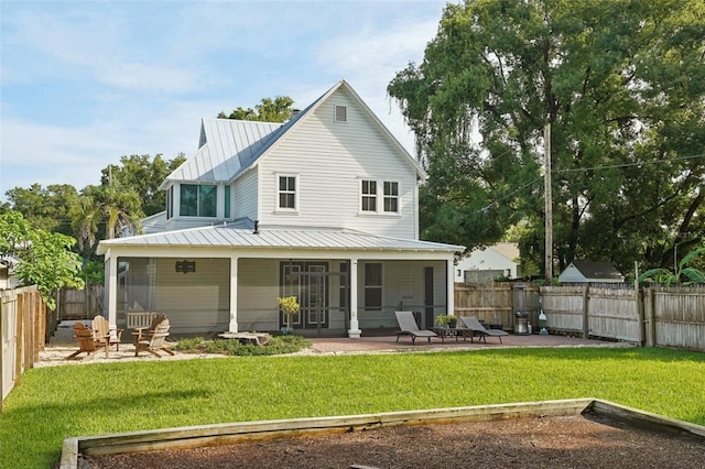 rear view of property featuring a yard, a patio, and a sunroom