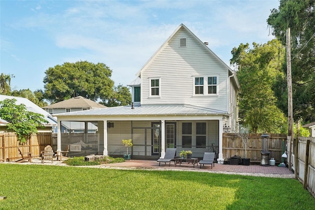 rear view of property featuring a lawn, a patio area, and a sunroom