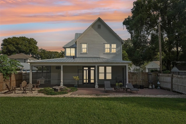 back house at dusk with a yard and a patio