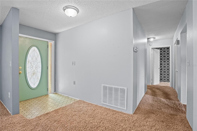 carpeted foyer featuring a textured ceiling