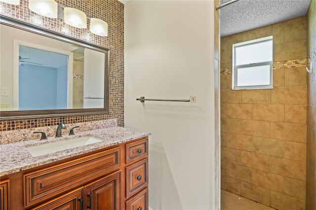 bathroom featuring vanity, decorative backsplash, a textured ceiling, and tiled shower