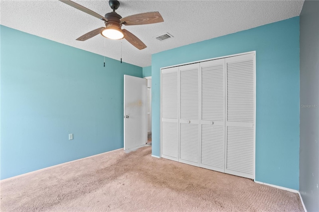 unfurnished bedroom featuring a closet, ceiling fan, a textured ceiling, and light colored carpet