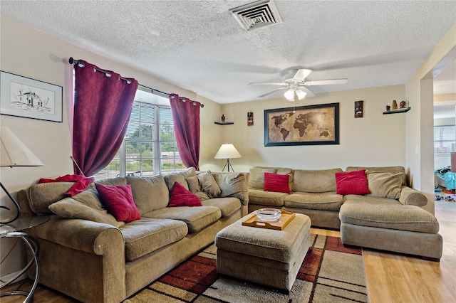 living room with ceiling fan, a textured ceiling, and light hardwood / wood-style flooring