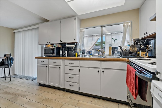 kitchen featuring white electric range, sink, backsplash, and white cabinets