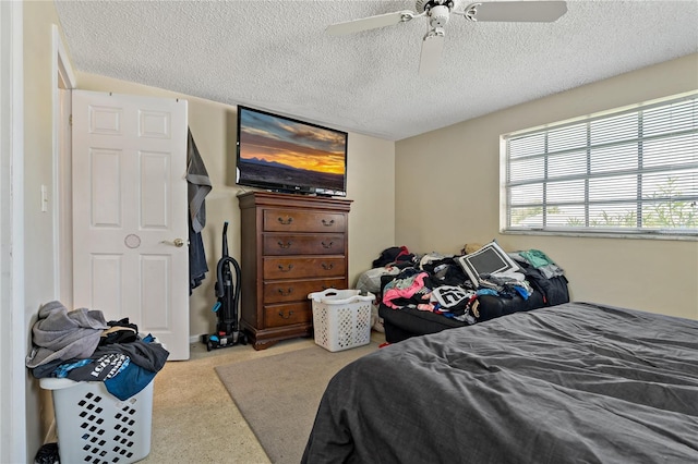 carpeted bedroom featuring ceiling fan and a textured ceiling