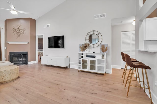 living room with high vaulted ceiling, light wood-type flooring, and ceiling fan