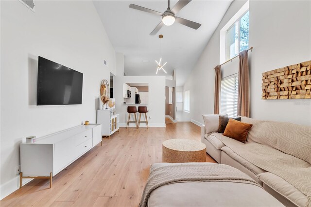 living room featuring light hardwood / wood-style floors, ceiling fan, a healthy amount of sunlight, and high vaulted ceiling