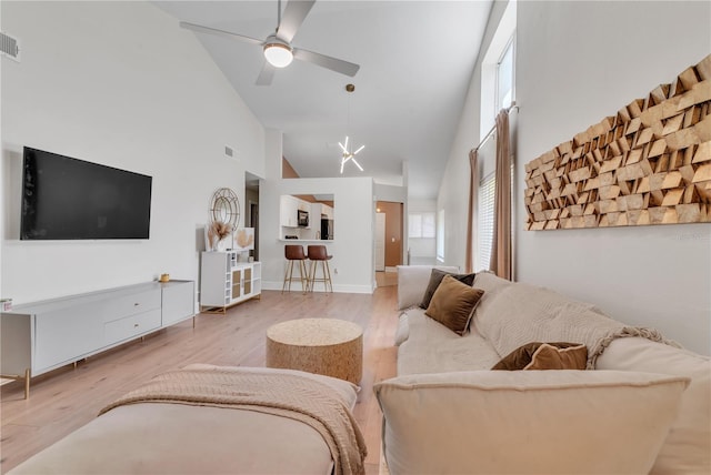 living room with high vaulted ceiling, ceiling fan, and light wood-type flooring