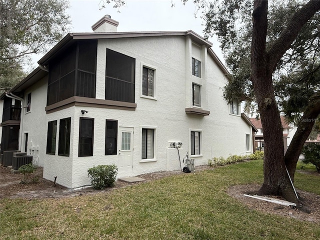 back of property featuring cooling unit and a lawn