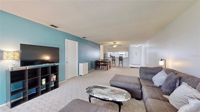 carpeted living room featuring ceiling fan and a textured ceiling