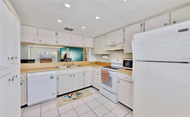 kitchen with sink, white cabinetry, light tile patterned floors, premium range hood, and white appliances