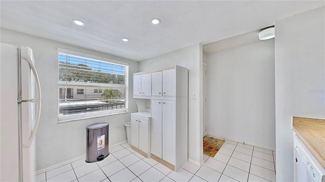 kitchen featuring white fridge, white cabinetry, and light tile patterned floors