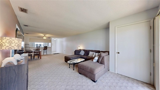 living area with a ceiling fan, carpet, visible vents, and a textured ceiling