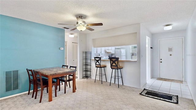 carpeted dining room featuring a textured ceiling, visible vents, and ceiling fan