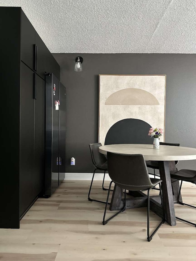 dining room with a textured ceiling and light wood-type flooring