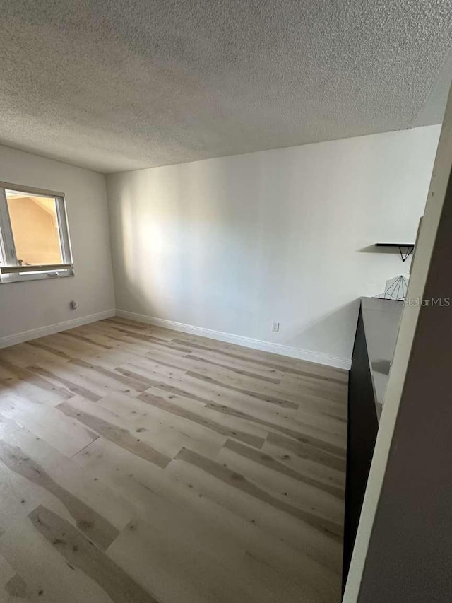 unfurnished room with light hardwood / wood-style floors and a textured ceiling