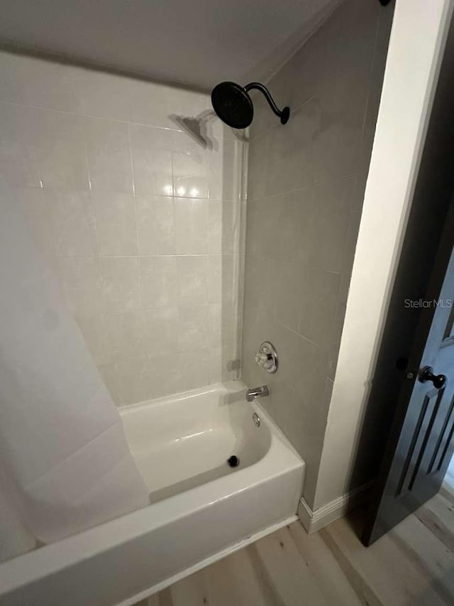 bathroom with hardwood / wood-style floors and tiled shower / bath combo