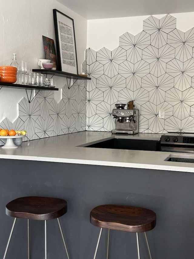 kitchen featuring a kitchen bar, stainless steel electric stove, and tasteful backsplash